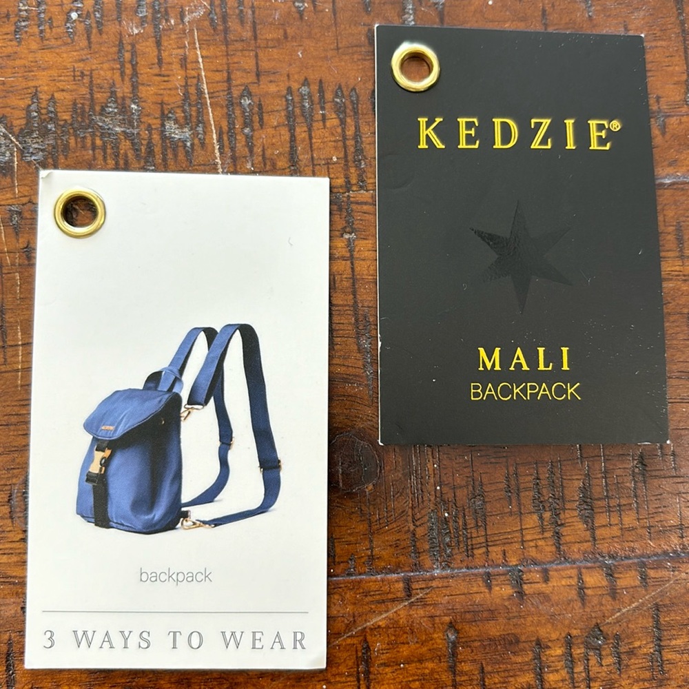 Kenzie purse/sling/backpack. Blue with gold. Approximately 10”x8”. Brand new.